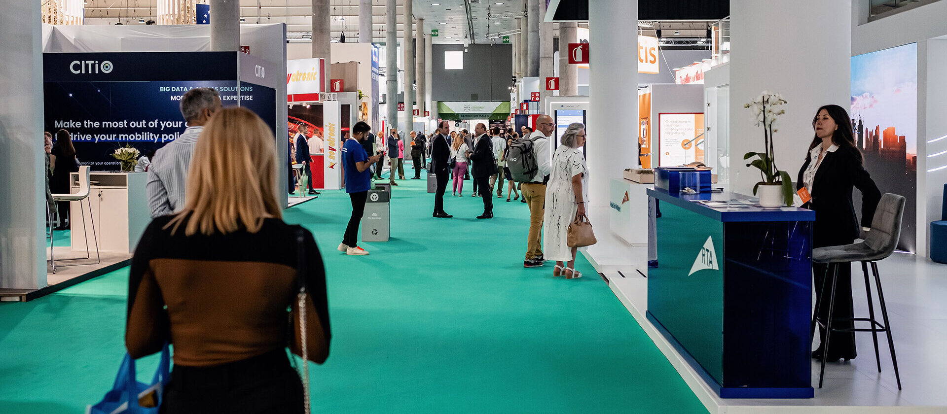 People walking around the exhibition halls, looking at booths at the UITP Summit.