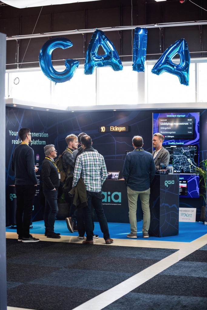 Gaia's booth at Persontrafik. Several visitors are standing and talking with Fredrik from Gaia.